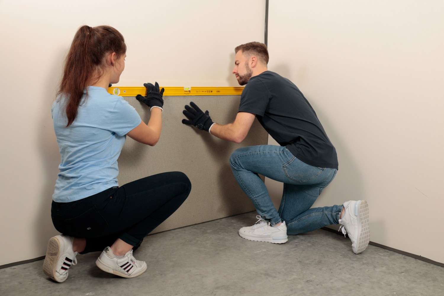 Two people installing a wall panel and aligning it with a spirit level. The image illustrates easy and precise installation in interior construction.