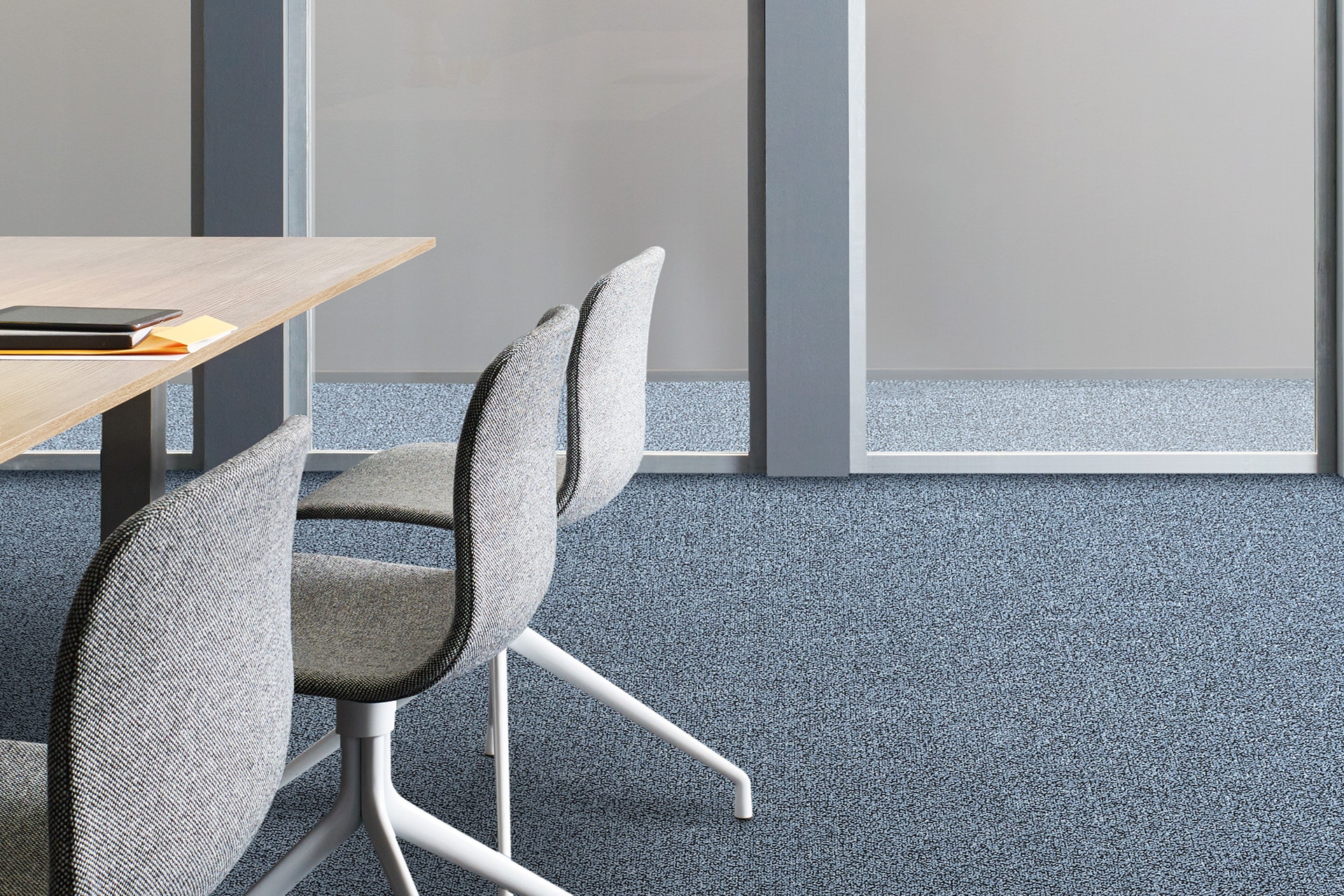 Moderner Konferenzraum mit grauen Polsterstühlen und Holztisch, ausgestattet mit blau-grau meliertem Teppichboden von Das Teppichwerk.