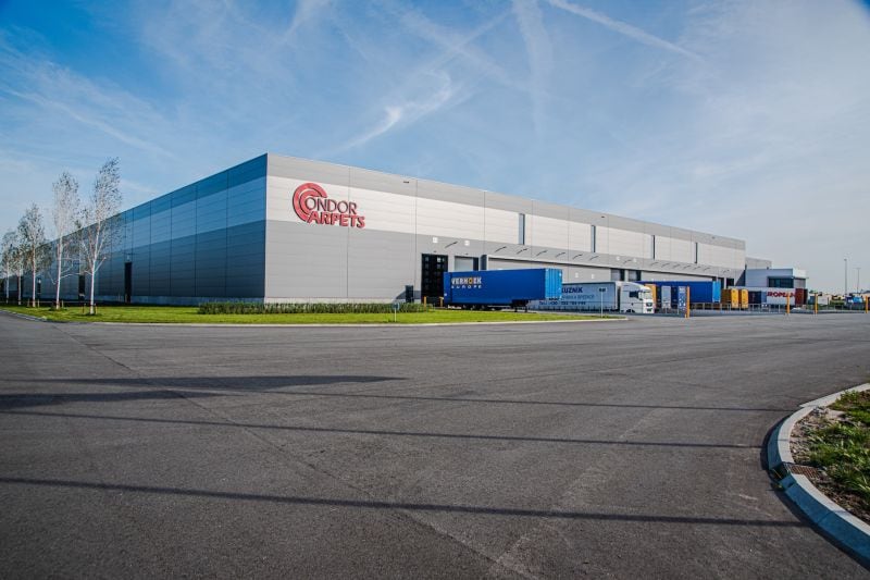 Exterior view of the Condor Group’s logistics and production facility. The modern industrial building with a clean façade design and prominent company logo represents efficient infrastructure and international flooring expertise.